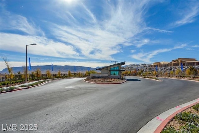 909 Allister Fields Ln, Las Vegas, NV 89138 - view of asphalt road with street lights, curbs, and a mountain view