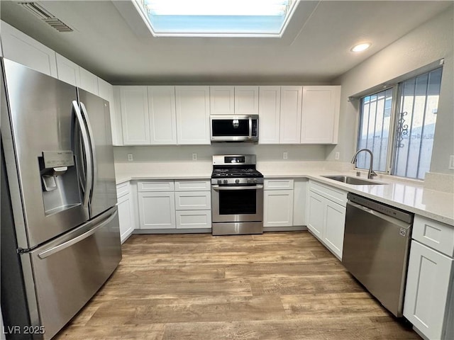 6063 Peach Orchard Rd, Las Vegas, NV 89142 - kitchen featuring stainless steel appliances, light countertops, white cabinets, light wood-style flooring, and recessed lighting