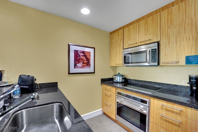 2000 N Fashion Show Dr Unit 2222, Las Vegas, NV 89109 - kitchen with appliances with stainless steel finishes, light tile patterned floors, light brown cabinetry, and dark stone countertops