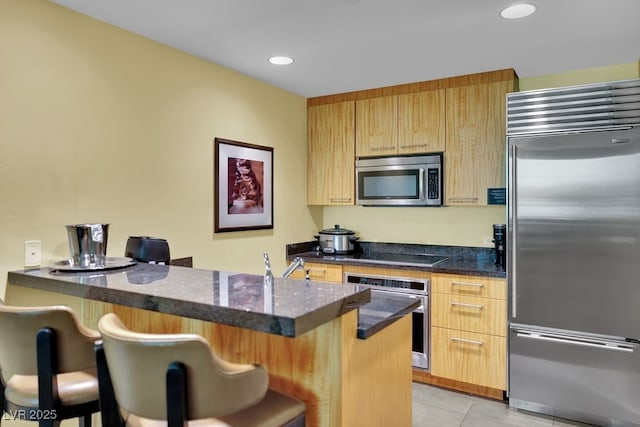 2000 N Fashion Show Dr Unit 2222, Las Vegas, NV 89109 - kitchen featuring appliances with stainless steel finishes, a breakfast bar, light tile patterned floors, light brown cabinets, and recessed lighting