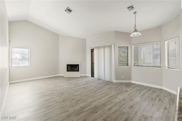5038 S Rainbow Blvd Unit 206, Las Vegas, NV 89118 - unfurnished living room featuring wood finished floors, vaulted ceiling, and a tiled fireplace