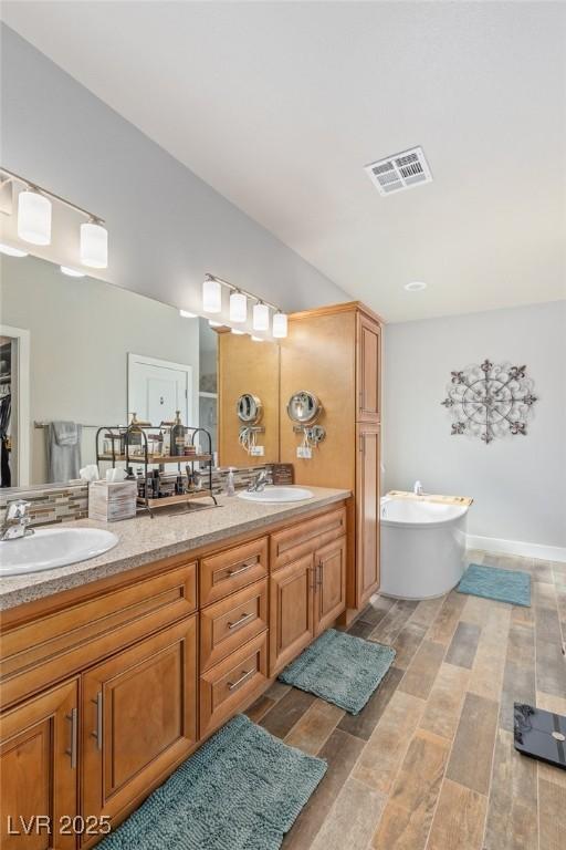 171 Weeping Willow Ct, Pahrump, NV 89048 - bathroom featuring double vanity, wood finished floors, and a freestanding tub