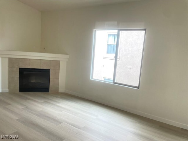 8985 S Durango Dr Unit 2043, Las Vegas, NV 89113 - unfurnished living room featuring a tiled fireplace and light wood-style flooring