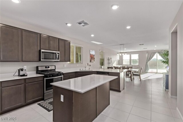 6909 Toll Mountain St, North Las Vegas, NV 89086 - kitchen with stainless steel appliances, a peninsula, a center island, light countertops, and dark brown cabinets