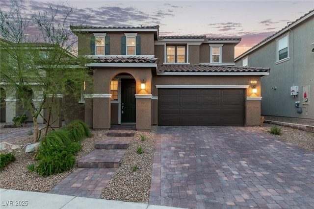 6909 Toll Mountain St, North Las Vegas, NV 89086 - mediterranean / spanish home featuring a tiled roof, stucco siding, decorative driveway, and a garage