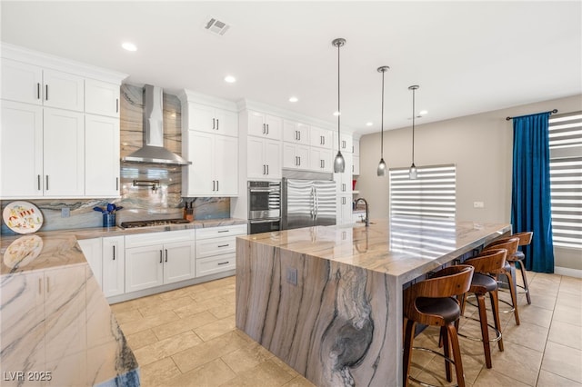 286 Bowsprit Ct, Las Vegas, NV 89183 - kitchen with stainless steel appliances, wall chimney exhaust hood, tasteful backsplash, a spacious island, and light stone countertops