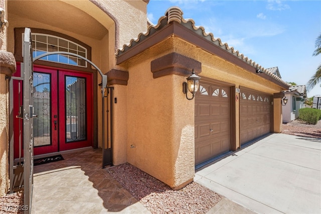 286 Bowsprit Ct, Las Vegas, NV 89183 - property entrance featuring stucco siding, a tile roof, a garage, concrete driveway, and french doors