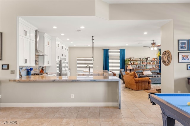 286 Bowsprit Ct, Las Vegas, NV 89183 - kitchen featuring wall chimney exhaust hood, light stone countertops, white cabinetry, a peninsula, and a ceiling fan