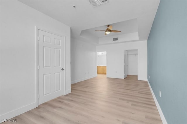 75 E Agate Ave Unit 206, Las Vegas, NV 89123 - unfurnished bedroom featuring a raised ceiling, light wood-style flooring, ensuite bathroom, ceiling fan, and a spacious closet