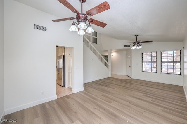 2501 Muirfield Ave, Henderson, NV 89074 - unfurnished living room featuring a ceiling fan, lofted ceiling, stairs, light wood finished floors, and a textured ceiling