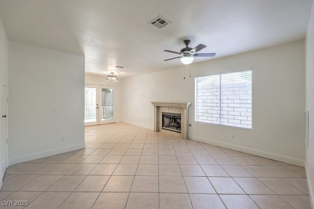 2501 Muirfield Ave, Henderson, NV 89074 - unfurnished living room featuring healthy amount of natural light, a tiled fireplace, a ceiling fan, and light tile patterned floors