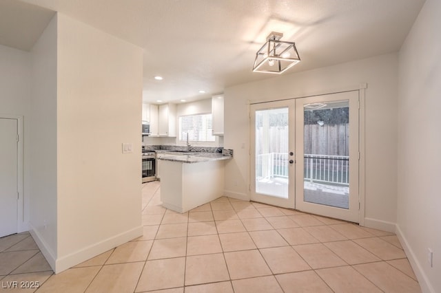 2501 Muirfield Ave, Henderson, NV 89074 - kitchen featuring appliances with stainless steel finishes, french doors, white cabinetry, light tile patterned floors, and a peninsula