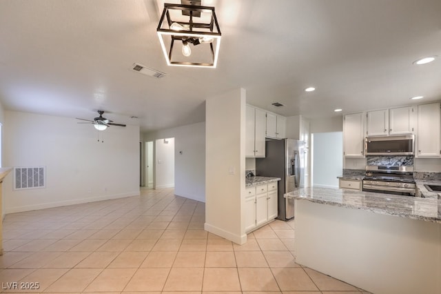 2501 Muirfield Ave, Henderson, NV 89074 - kitchen with appliances with stainless steel finishes, light tile patterned floors, recessed lighting, light stone counters, and white cabinets