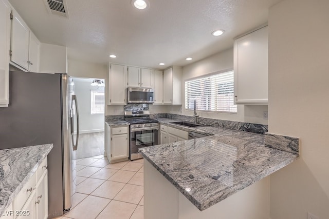 2501 Muirfield Ave, Henderson, NV 89074 - kitchen with stainless steel appliances, plenty of natural light, light stone counters, light tile patterned floors, and recessed lighting
