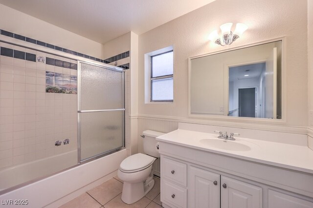 2501 Muirfield Ave, Henderson, NV 89074 - bathroom featuring vanity, tile patterned flooring, bath / shower combo with glass door, and a wainscoted wall