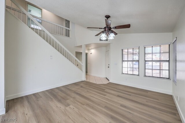 2501 Muirfield Ave, Henderson, NV 89074 - unfurnished living room with stairs, a ceiling fan, lofted ceiling, and wood finished floors