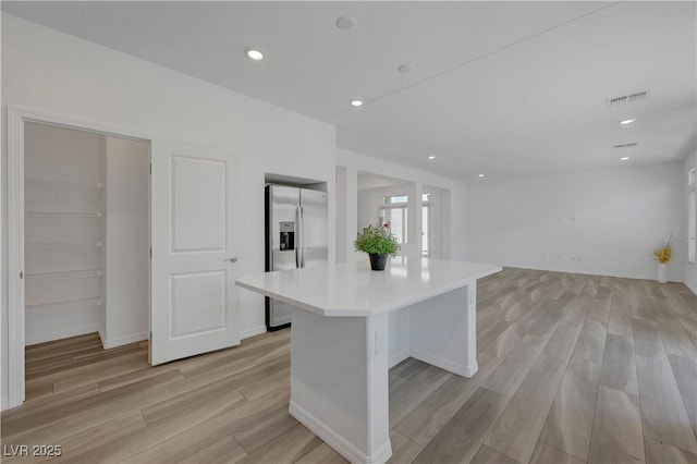 629 Soaring Wings Ave, Las Vegas, NV 89183 - kitchen featuring stainless steel fridge with ice dispenser, light countertops, light wood finished floors, a center island, and recessed lighting