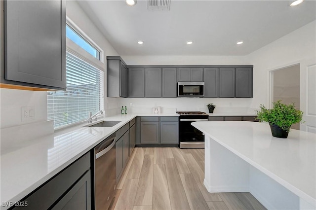 629 Soaring Wings Ave, Las Vegas, NV 89183 - kitchen with appliances with stainless steel finishes, recessed lighting, light countertops, light wood finished floors, and gray cabinetry