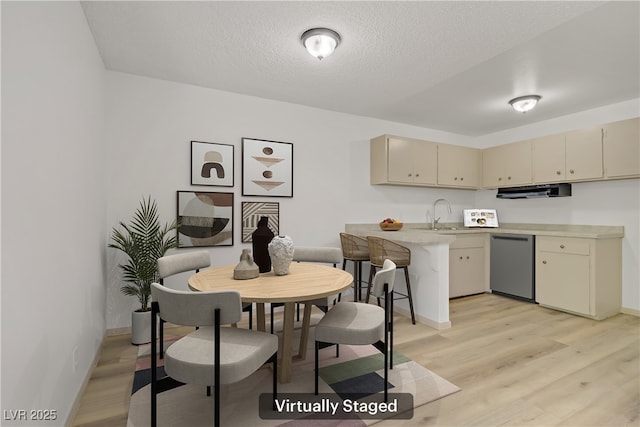 304 Orland St Unit 47, Las Vegas, NV 89107 - kitchen with dishwasher, cream cabinets, light countertops, light wood finished floors, and under cabinet range hood