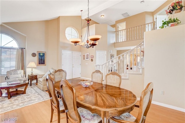 8416 Dry Cliff Cir, Las Vegas, NV 89128 - dining room with light wood-type flooring, plenty of natural light, a chandelier, stairway, and high vaulted ceiling