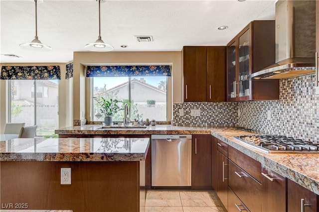 8416 Dry Cliff Cir, Las Vegas, NV 89128 - kitchen with appliances with stainless steel finishes, wall chimney exhaust hood, decorative light fixtures, tasteful backsplash, and glass insert cabinets
