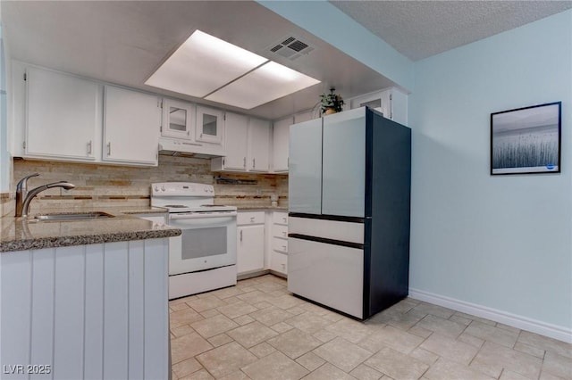 4742 Obannon Dr Unit A, Las Vegas, NV 89102 - kitchen featuring freestanding refrigerator, electric range, under cabinet range hood, decorative backsplash, and white cabinetry