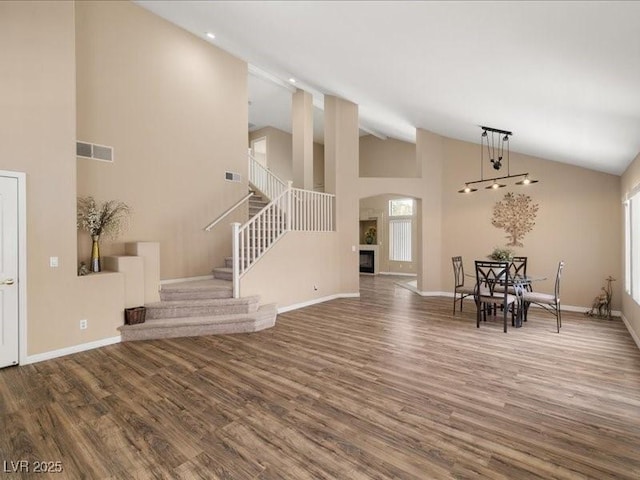 7924 Mcdowell Dr, Las Vegas, NV 89129 - unfurnished living room with wood finished floors, high vaulted ceiling, stairway, and arched walkways