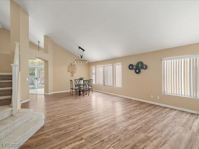 7924 Mcdowell Dr, Las Vegas, NV 89129 - unfurnished living room with stairway, wood finished floors, arched walkways, and high vaulted ceiling