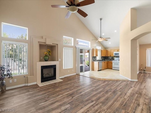 7924 Mcdowell Dr, Las Vegas, NV 89129 - unfurnished living room with ceiling fan, high vaulted ceiling, light wood-type flooring, a fireplace, and arched walkways