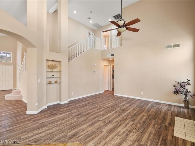 7924 Mcdowell Dr, Las Vegas, NV 89129 - unfurnished living room with arched walkways, high vaulted ceiling, wood finished floors, ceiling fan, and stairs