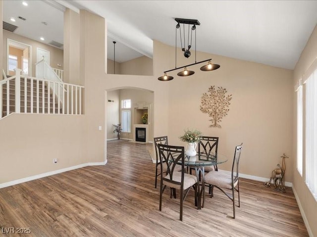 7924 Mcdowell Dr, Las Vegas, NV 89129 - dining area featuring wood finished floors, arched walkways, a glass covered fireplace, and high vaulted ceiling