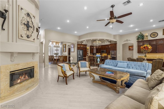 1329 Calle Cantar, Henderson, NV 89012 - living room featuring arched walkways, ceiling fan, a premium fireplace, light tile patterned floors, and a chandelier