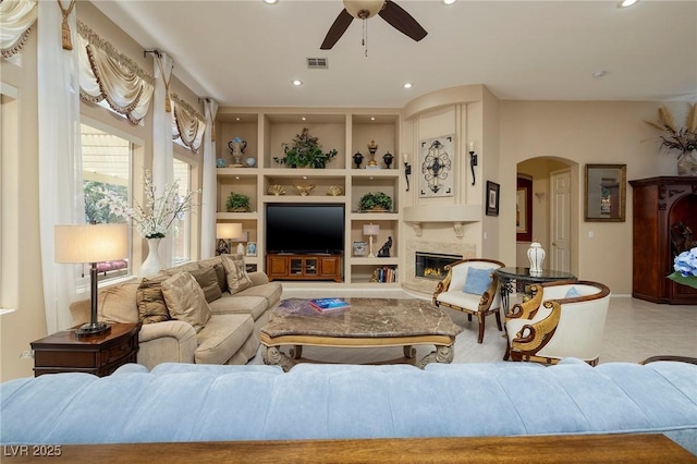 1329 Calle Cantar, Henderson, NV 89012 - living area with ceiling fan, arched walkways, built in features, recessed lighting, and a glass covered fireplace