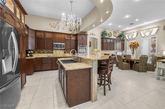 1329 Calle Cantar, Henderson, NV 89012 - kitchen with appliances with stainless steel finishes, a chandelier, arched walkways, backsplash, and a breakfast bar area