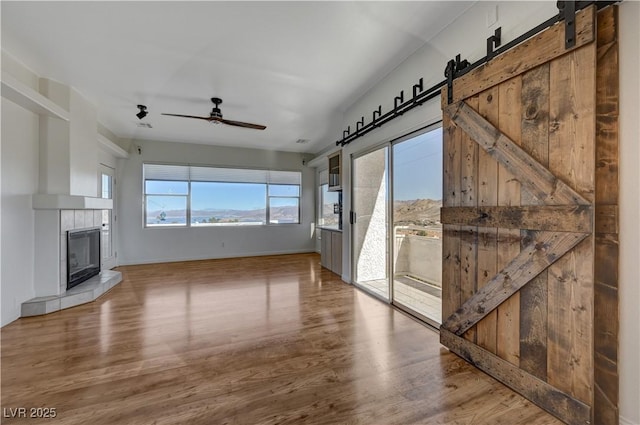 483 Marina Cv, Boulder City, NV 89005 - unfurnished living room featuring a barn door, wood finished floors, ceiling fan, and a fireplace