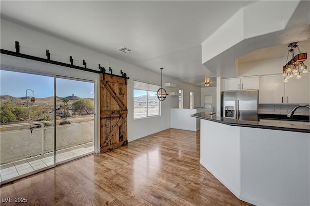 483 Marina Cv, Boulder City, NV 89005 - kitchen featuring stainless steel fridge with ice dispenser, dark countertops, a chandelier, light wood finished floors, and hanging light fixtures