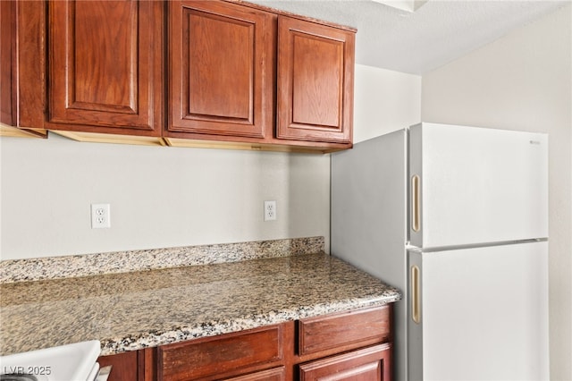 6800 E Lake Mead Blvd Unit 1018, Las Vegas, NV 89156 - kitchen featuring freestanding refrigerator, light stone counters, and brown cabinetry