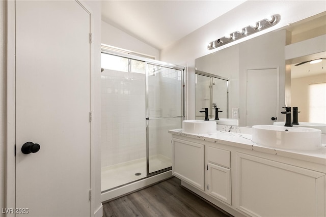 4825 White Aspen Ave, Las Vegas, NV 89130 - bathroom featuring a stall shower, vaulted ceiling, double vanity, and wood finished floors