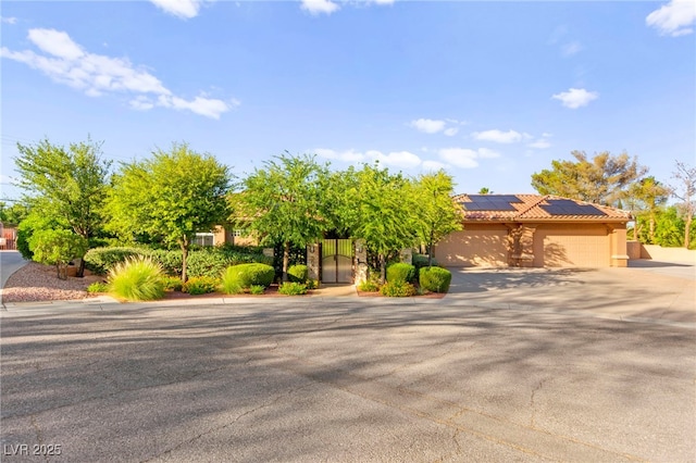 5680 N Fort Apache Rd, Las Vegas, NV 89149 - view of property hidden behind natural elements featuring concrete driveway, roof mounted solar panels, an attached garage, a tile roof, and stucco siding