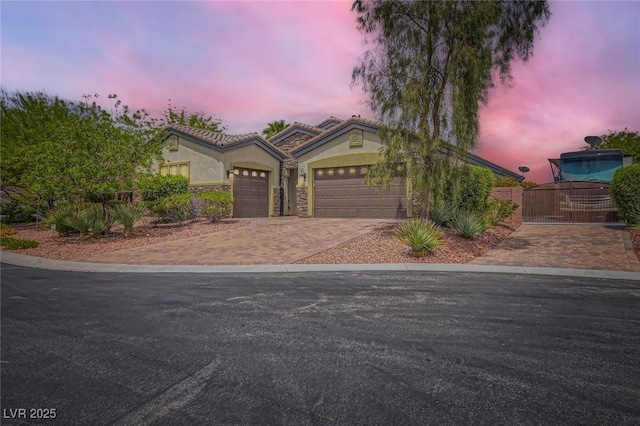 8732 Kendall Brook Cir, Las Vegas, NV 89149 - view of front of house with stucco siding, an attached garage, decorative driveway, a gate, and stone siding