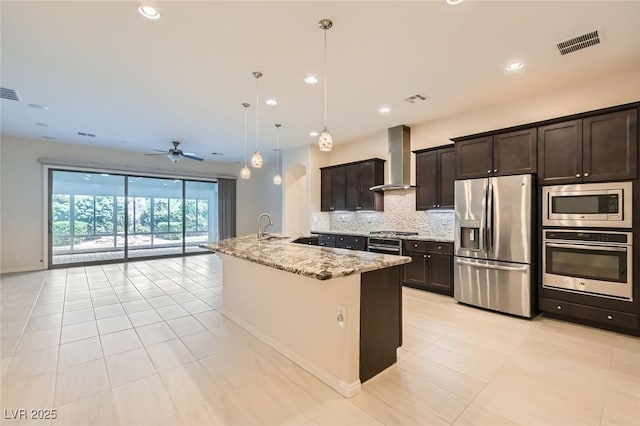 8732 Kendall Brook Cir, Las Vegas, NV 89149 - kitchen with appliances with stainless steel finishes, wall chimney range hood, backsplash, open floor plan, and light stone countertops