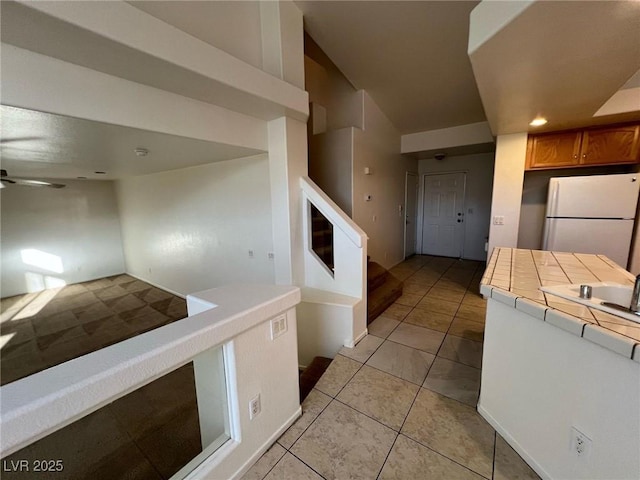 8704 Autumn Wreath Ave, Las Vegas, NV 89129 - kitchen featuring freestanding refrigerator, tile countertops, a ceiling fan, light tile patterned floors, and brown cabinetry