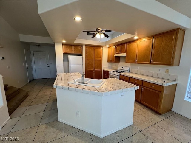 8704 Autumn Wreath Ave, Las Vegas, NV 89129 - kitchen featuring white appliances, tile countertops, a ceiling fan, light tile patterned floors, and a raised ceiling