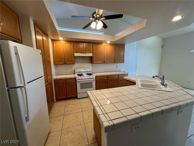 8704 Autumn Wreath Ave, Las Vegas, NV 89129 - kitchen featuring white appliances, tile countertops, under cabinet range hood, a tray ceiling, and a ceiling fan