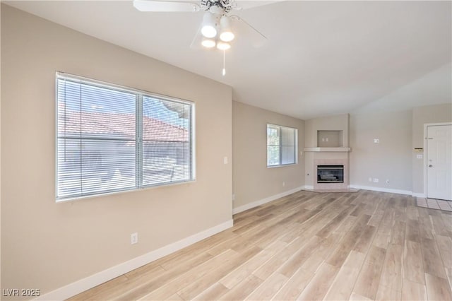 370 Manti Pl Unit 21, Henderson, NV 89014 - unfurnished living room featuring ceiling fan, light wood-style floors, a glass covered fireplace, and vaulted ceiling