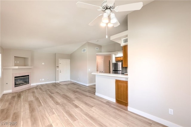 370 Manti Pl Unit 21, Henderson, NV 89014 - unfurnished living room featuring a ceiling fan, light wood-style floors, lofted ceiling, and a glass covered fireplace