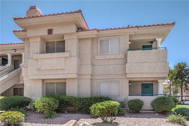 370 Manti Pl Unit 21, Henderson, NV 89014 - view of front of house with a chimney, a balcony, a tiled roof, and stucco siding