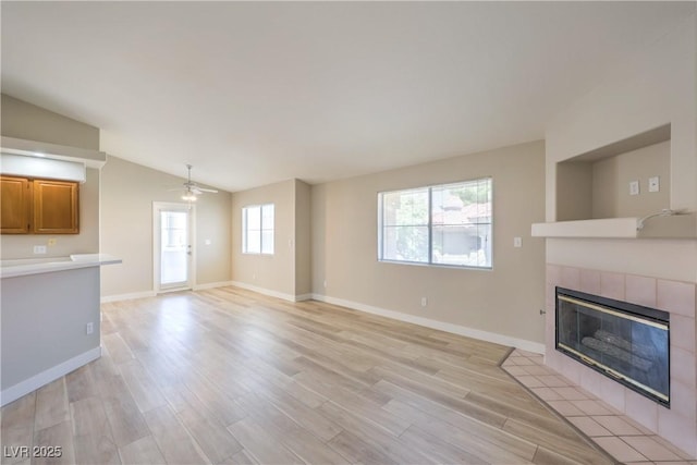 370 Manti Pl Unit 21, Henderson, NV 89014 - unfurnished living room featuring vaulted ceiling, a tiled fireplace, ceiling fan, and light wood finished floors