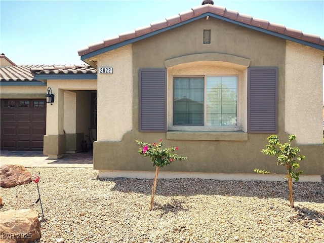 2822 Chetco River St, Laughlin, NV 89029 - view of side of home featuring stucco siding, a tile roof, and a garage