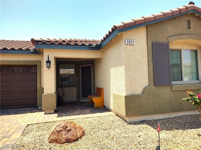 2822 Chetco River St, Laughlin, NV 89029 - doorway to property featuring stucco siding, a garage, and a tiled roof